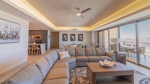 A spacious living area with a large sectional sofa, a dining table, and a view of the city through large windows. - Sonoran Star 1-0805-3Bed (Puerto Peñasco)