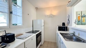 Eine kleine Küche mit Kühlschrank, Mikrowelle, Backofen und Spüle.
