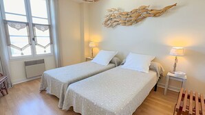 Ein Doppelzimmer mit zwei Betten, einer Wanddekoration, Nachttischlampen und einem Fenster mit Blick.