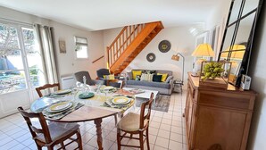 Ein Essbereich mit einem Tisch für vier Personen, einer Couch, einer Treppe und einer Lampe.