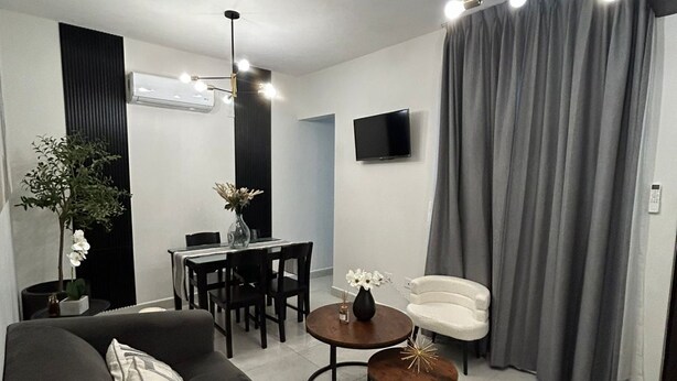 Een moderne woonkamer met een bank, salontafel en een eethoek.