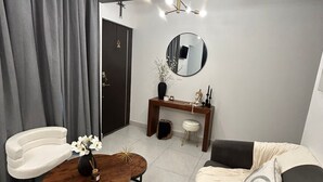 Een moderne woonkamer met een bank, een ronde salontafel, een stoel, een spiegel en een console met decoratieve objecten.