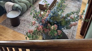 Een woonkamer met een bank, een salontafel, een fauteuil, een televisie en een decoratieve plant.