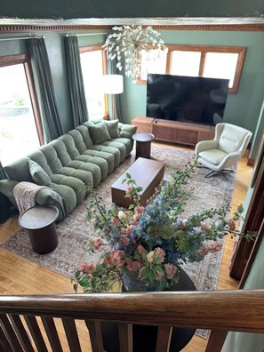 A living room with a sofa, a coffee table, a chair, a TV, and a decorative plant.
