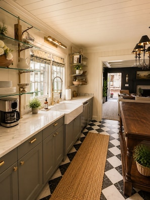 A kitchen with a checkered floor, a coffee maker, and a sink.