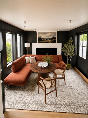 A modern living room with a sectional sofa, a round wooden coffee table, and a fireplace.
