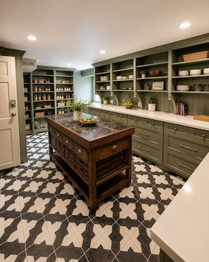 A kitchen with a central island, green cabinetry, and a patterned floor.