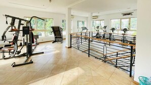 Et rummeligt fitnesscenter med forskellig træningsudstyr, store vinduer og et flisegulv.