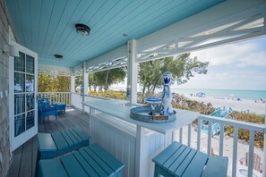 A covered outdoor area with seating, a decorative fountain, and a view of the beach. - Happy Ours – NEW LISTING, Direct Beachfront Home On Magnolia (Anna Maria)