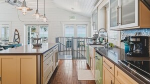 A kitchen with a central island, stainless steel appliances, and a view to the outside. - Happy Ours – NEW LISTING, Direct Beachfront Home On Magnolia (Anna Maria)