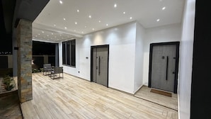 A modern building with a covered patio area, stone pillar, and two doors.