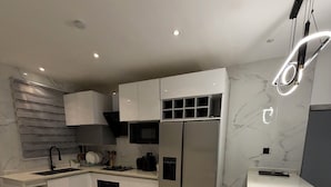 A modern kitchen with a marble floor, stainless steel appliances, and a bar area.