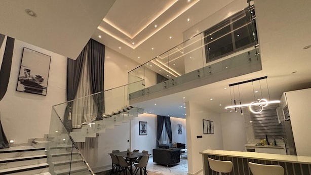 A modern interior with a glass staircase, a dining area, and a kitchen.