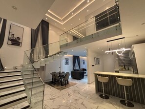 A modern interior with a glass staircase, a dining area, and a kitchen. - 3-bedroom house in beautiful Pakyi No.2 perfect for relaxing stays (Pakyi No.2)