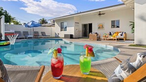 A swimming pool with lounge chairs, a table with drinks, and a patio area with a ceiling fan. - Scottsdale-4BR Retreat-Pool, Fire Pit, Pool Table, Shuffle board, BBQ (Scottsdale)