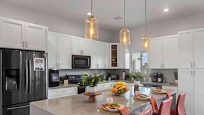 A modern kitchen with white cabinets, stainless steel appliances, a central island with seating, and pendant lighting. - Scottsdale-4BR Retreat-Pool, Fire Pit, Pool Table, Shuffle board, BBQ (Scottsdale)