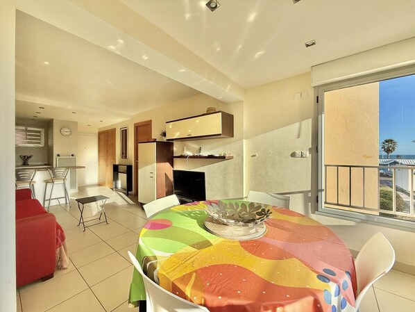 Ein moderner Essbereich mit farbenfroher Tischdecke, eine Küche im Hintergrund und ein Balkon mit Blick.