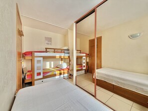 Ein Zimmer mit Etagenbetten, einer Schiebetür und einem kleinen Tisch.
