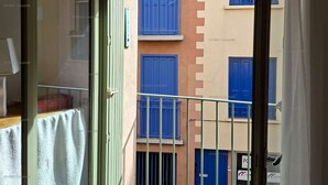 Un balcón con vistas a edificios cercanos, una puerta y una ventana con una toalla.