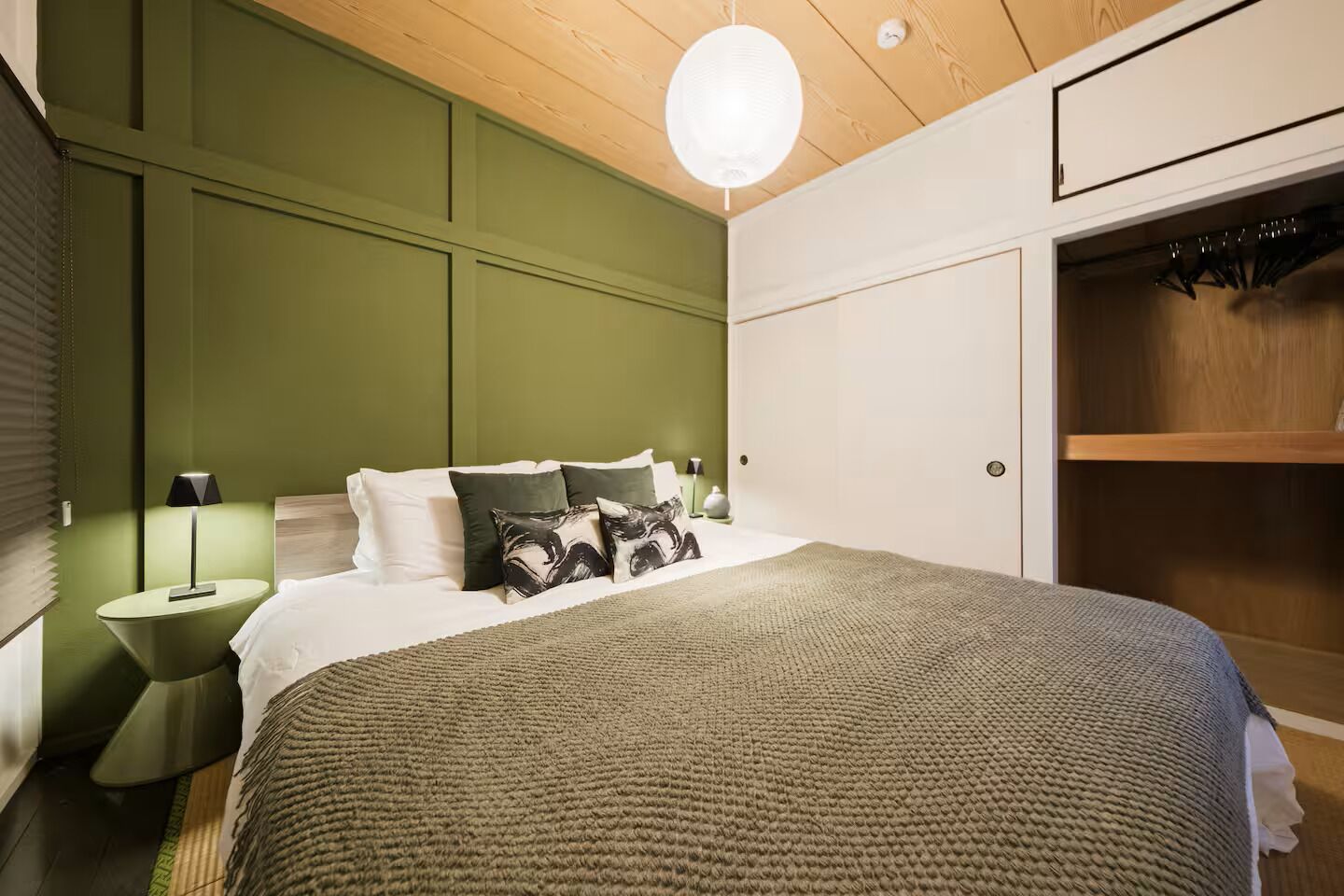 Une chambre à coucher comprenant un lit, des lampes de chevet, un luminaire suspendu et une armoire.