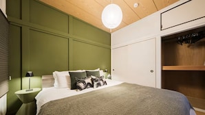A bedroom with a bed, bedside lamps, a hanging light fixture, and a wardrobe.