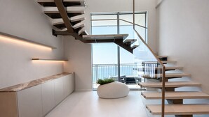 A modern interior with a spiral staircase, a kitchen area, and a view to the outside. - Exclusive Palm View Penthouse, Terrace & Pool (Dubai)