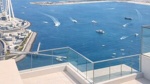A high-rise building with a glass balcony overlooking a marina with boats and a city skyline in the background. - Exclusive Palm View Penthouse, Terrace & Pool (Dubai)