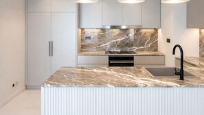 A modern kitchen with a marble countertop, stainless steel appliances, and pendant lighting. - Exclusive Palm View Penthouse, Terrace & Pool (Dubai)