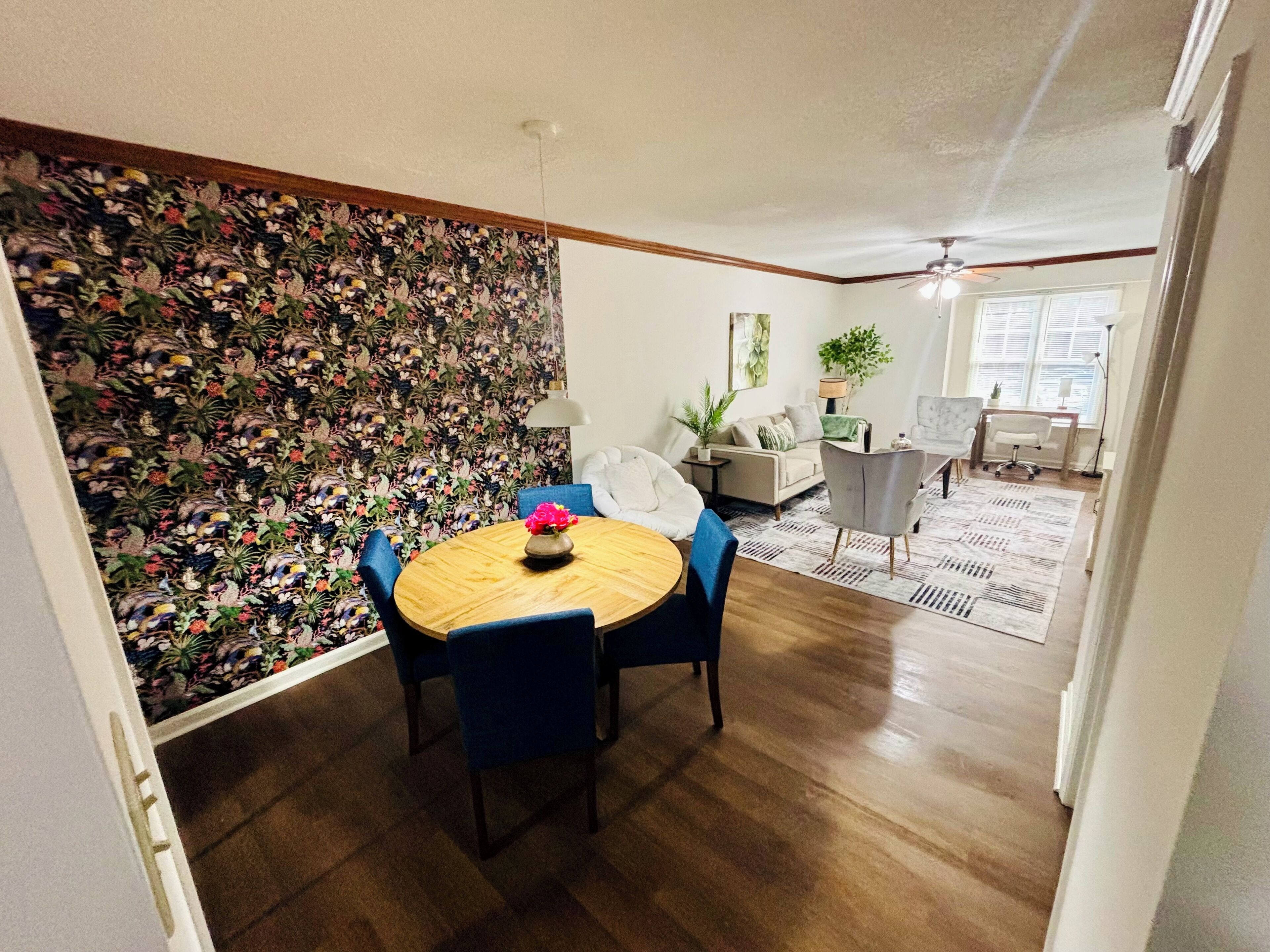 A dining area with a round table, chairs, and a floral wallpaper.
