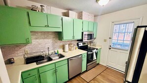 Une cuisine avec des meubles de couleur verte, un four à micro-ondes, un lave-vaisselle et un réfrigérateur.