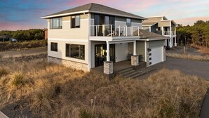 A two-story house with a balcony, a garage, and a driveway. - Oceanview Retreat - Hot Tub + Game Garage + Spa Suite + Kids Cave - Westport, WA (Westport)