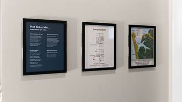 Three framed informational posters on a wall: one about hot tub safety rules, one showing emergency exits on the second floor, and one with a map of the area.