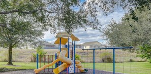 A playground with a slide, swings, and climbing structures. - Inviting 3-Bedroom Oasis on top floor (Davenport)