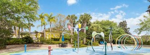A playground with colorful equipment, a blue pool, and a building with yellow walls in the background. - Inviting 3-Bedroom Oasis on top floor (Davenport)