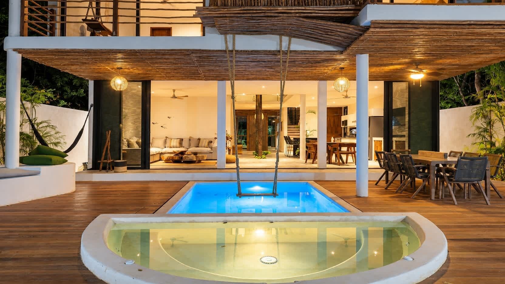 Pool and outdoor dining table beautifully lit at night