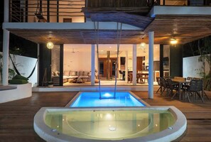 A modern indoor pool with a glass enclosure, wooden flooring, and a dining area with chairs and tables. - Zazil: Private Pool & Gated Jungle Luxury (Tulum)