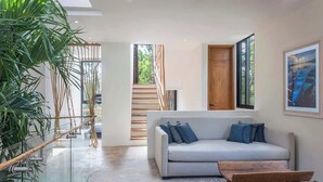 Ein modernes Wohnzimmer mit einer Couch, einer hölzernen Bank und einem Geländer aus Glas mit Pflanzen.