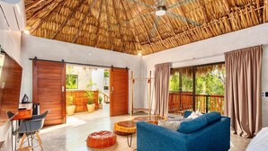 A modern room with a thatched ceiling, a blue sofa, a wooden desk, and large windows. - Casa Veleta: Designer Villa with Pool & Jacuzzi (Tulum)