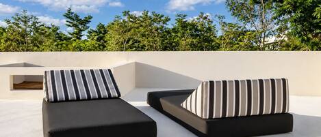 Two black lounge chairs with striped cushions on a rooftop terrace.
