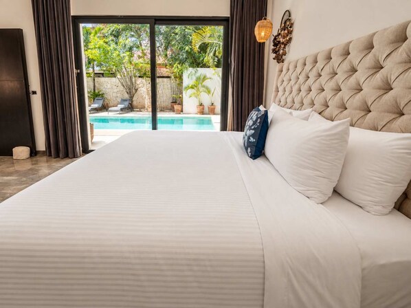 A bedroom with a large bed, a view of a swimming pool, and a door leading to an outdoor area. - Renovated Modern Villa · 4BR · Huge Pool · Gated (Tulum)