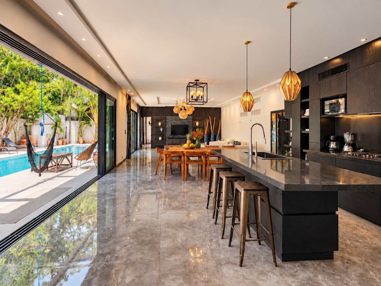 Una cucina moderna con isola centrale, sgabelli da bar e zona pranzo.