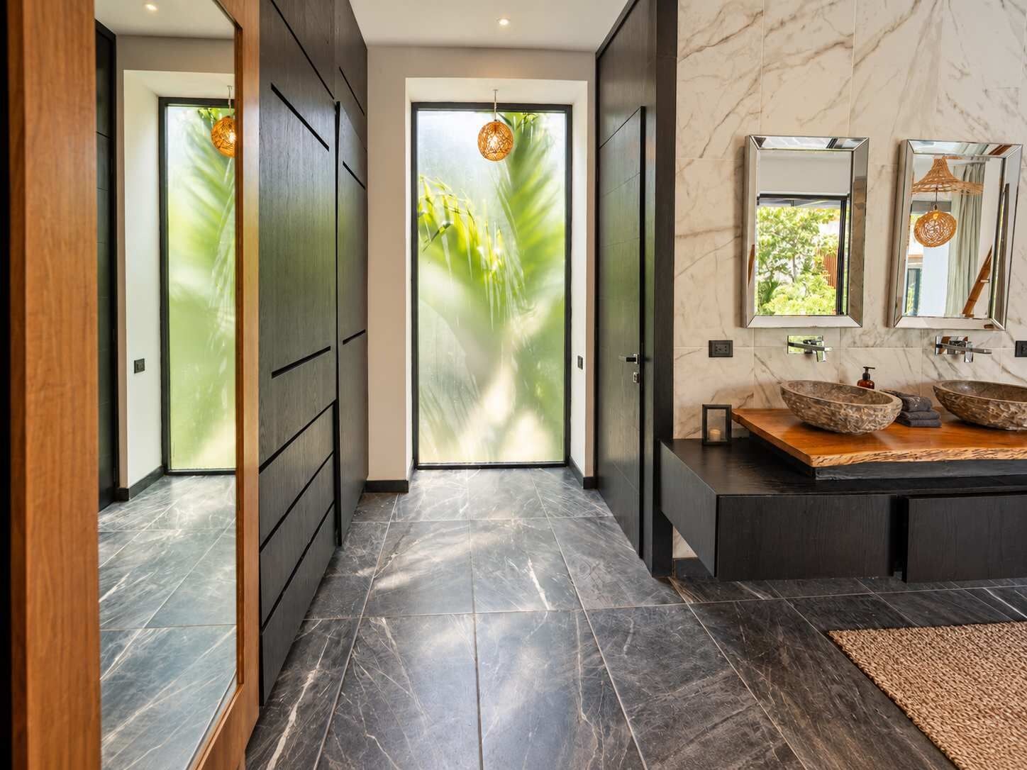 Un bagno moderno con un grande specchio, due lavabi a incasso e un mobile bagno in legno.