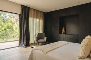 Ein modernes Schlafzimmer mit einem großen Bett, einem Sessel, einer dunklen Wand und einem Fenster mit Vorhängen.