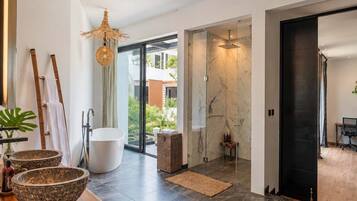A modern bathroom with a glass shower enclosure, a marble wall, and a wooden vanity with bowls.
