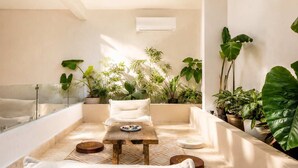 A spa area with a wooden table, white sofa, and various potted plants. - Villa con Limpieza Concierge y  Jacuzzi (Tulum)