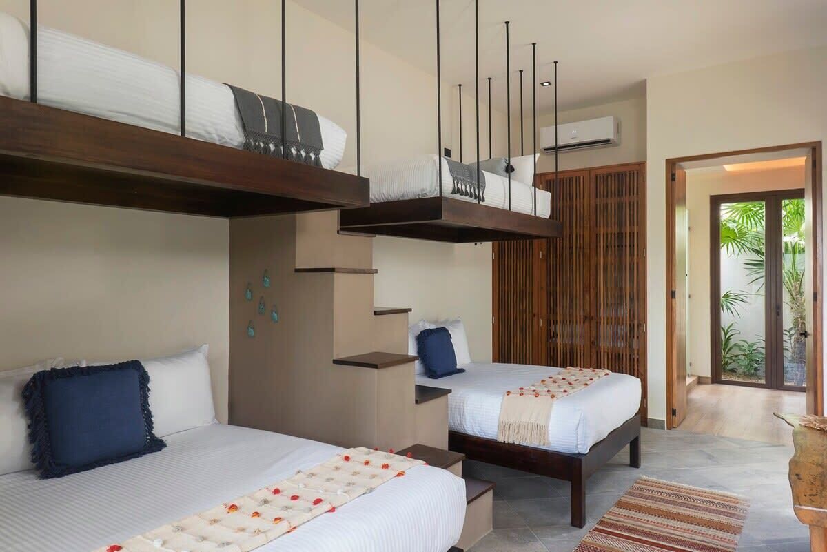 A hotel room with two beds, a wooden ceiling, and a view of greenery outside.