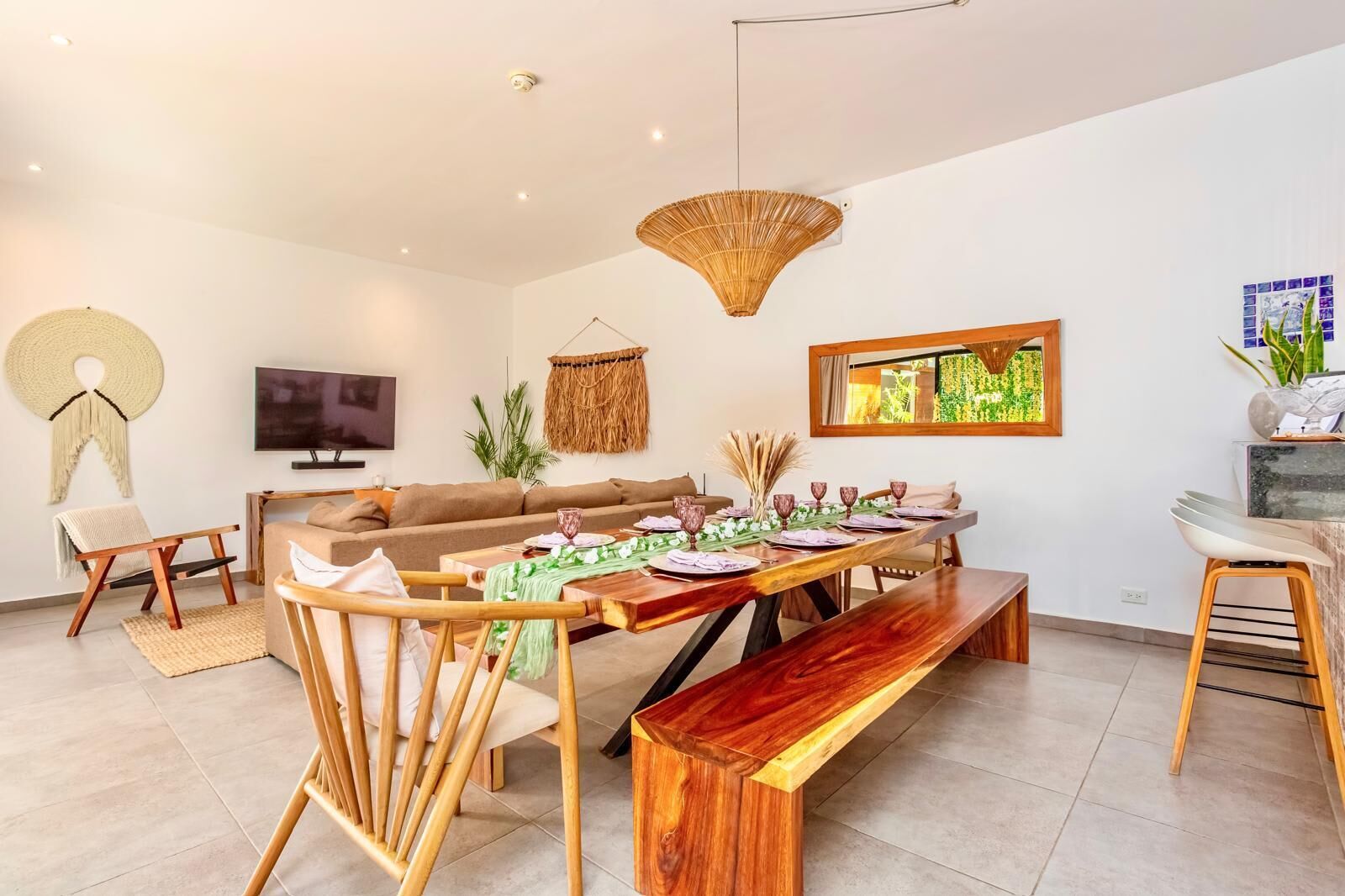Un salon moderne comprenant un canapé, une table à manger et des chaises, un téléviseur et un luminaire suspendu.