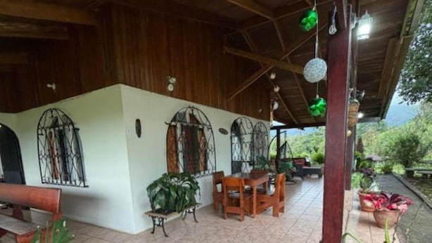 Ein überdachter Patio-Bereich mit Holzboden, Fliesenboden und Pflanzen in Töpfen.