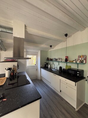 Een moderne keuken met een zwart aanrecht, witte kasten en een roestvrijstalen afzuigkap.