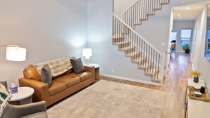 Un salon moderne avec un canapé en cuir marron, une table basse ronde et un escalier menant à un autre niveau.